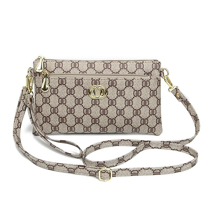 URHER Dion vintage print mini crossbody bag with gold hardware and adjustable strap. Beige and brown monogram pattern.