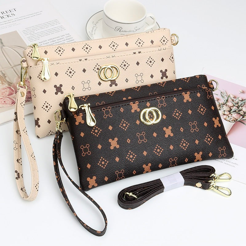 URHER Dion vintage print mini crossbody bag in brown and beige with gold hardware and chain strap.