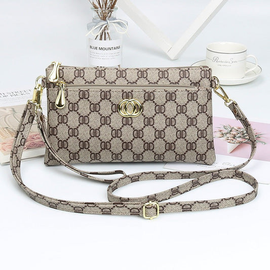 URHER Dion vintage print mini crossbody bag with gold hardware and adjustable strap. Beige and brown monogram pattern.