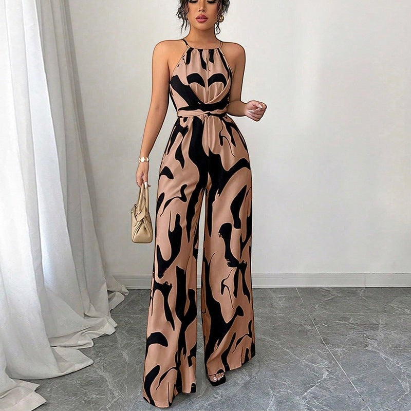 URHER Nia Utility Jumpsuit in tan with black abstract print, halter neck, wide legs, and tie waist. Model wearing jumpsuit with handbag.