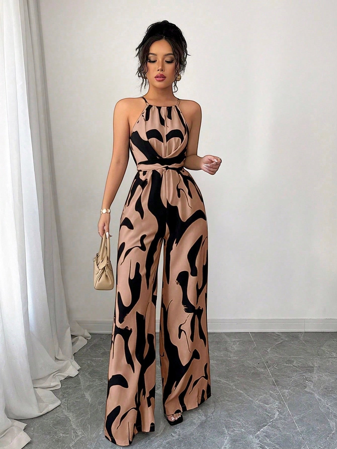 URHER Nia Utility Jumpsuit in tan with black abstract print, halter neck, wide legs, and tie waist.