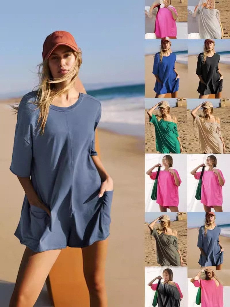 URHERE Imani Easy Jumpsuit in blue, a relaxed fit one-piece with short sleeves and pockets, styled on a beach.
