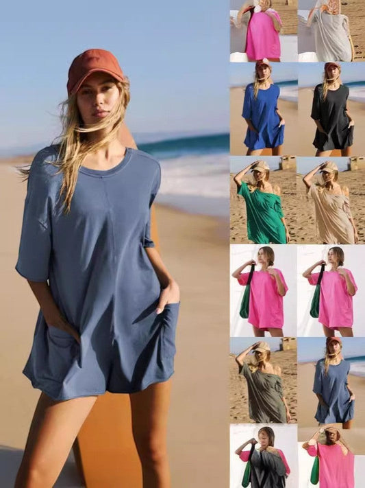 URHERE Imani Easy Jumpsuit in blue, a relaxed fit one-piece with short sleeves and pockets, styled on a beach.