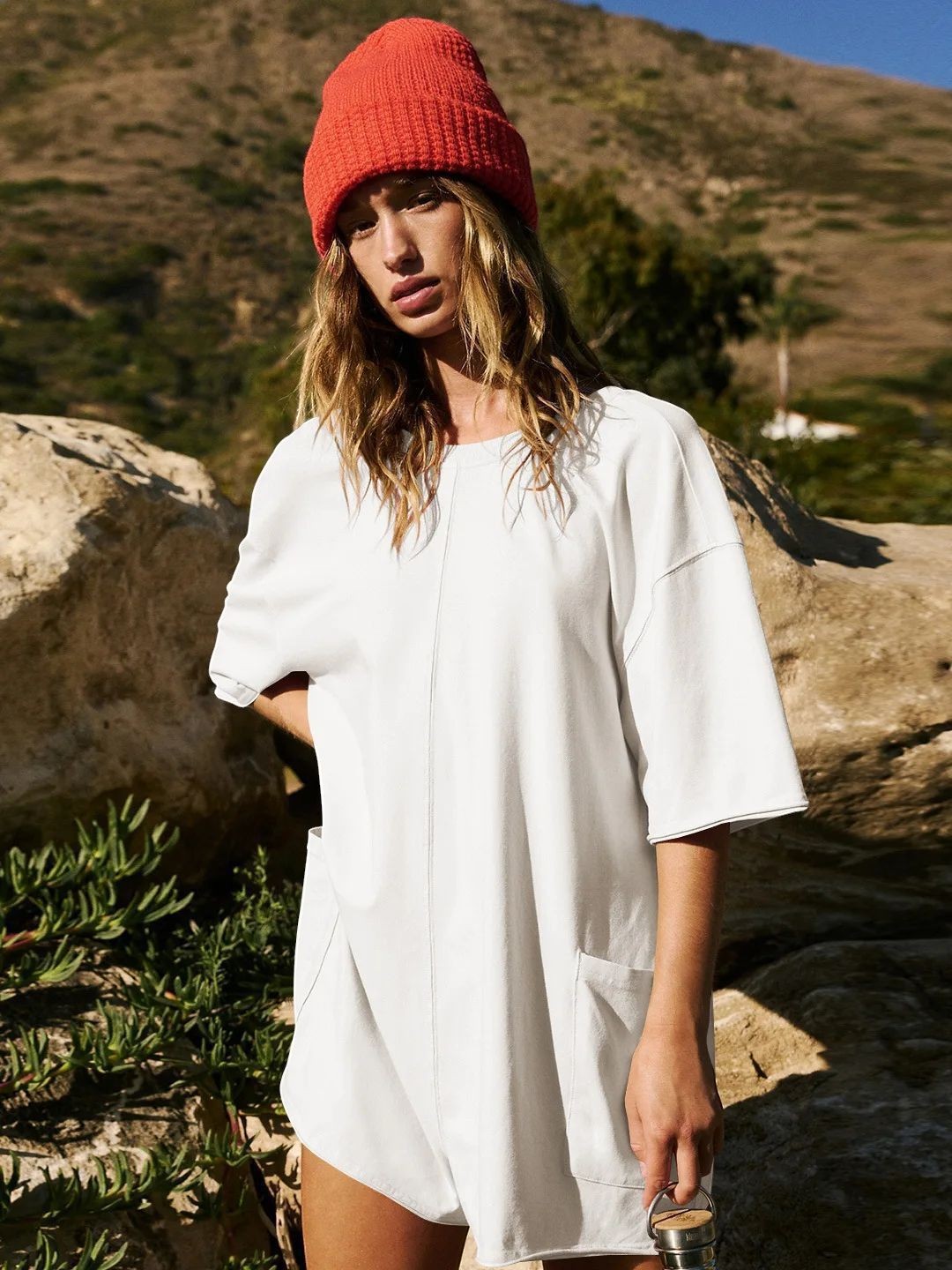 URHERE white relaxed fit short jumpsuit with pockets and short sleeves, worn by a model with a red beanie outdoors.